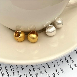 Detail of gold and silver brushed metal hoop earrings on a white ceramic plate
