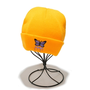 Détail du bonnet en tricot jaune avec broderie papillon violet et lettres