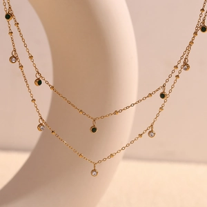 Close-up of dual-layer 18K gold-plated necklace featuring green and white cubic zirconia