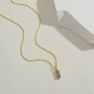 Close-up of gold eggplant pendant with purple and green pavé zircons on chain