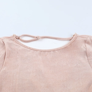 Detail of adjustable thin shoulder straps and round neckline on a champagne bodysuit