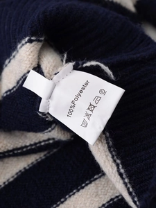 Detail of navy and beige striped knit cardigan showing 100% polyester care label