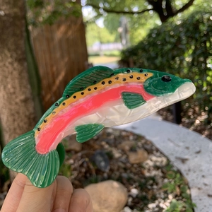 Rainbow trout claw clip made of multicolor pearlized acetate shown in a natural setting