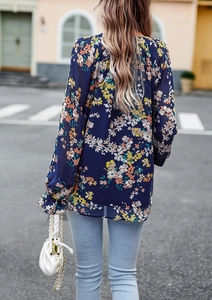 Dettaglio della camicia a fiori con maniche lunghe, polsini a balze ed elegante stampa