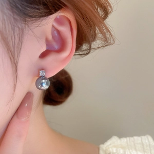 Detail shot of a model wearing grey pearl earrings with a sparkling zircon accent