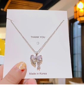 Détail du pendentif nœud argenté avec zircons sur une carte à bijoux blanche