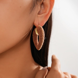 Close-up of a brown flocked heart earring with gold bead trim on a model's ear