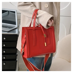 Detail of red fashion crossbody bag with golden hardware and wide fabric strap