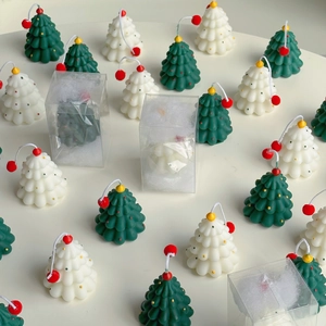 Detail of Christmas tree shaped candles in green and white colors with gift packaging