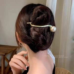 Elegant gold S-shaped pearl hair clip shown on model in a soft lit indoor setting