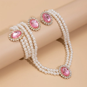 Detail view of vintage triple-layer faux pearl necklace with pink oval gemstones