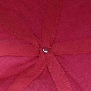Detail of internal crown stitching and metal rivet on rose red washed cotton baseball cap