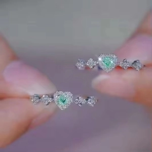Macro shot of double heart-shaped green emerald rings with fine diamond accents