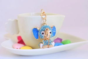 Close-up of elephant keychain with light blue rhinestones on a white coffee cup
