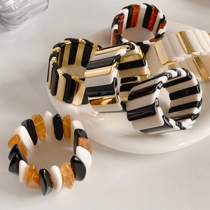 Close-up of geometric stretch bracelets in gold, amber, and black resin blocks