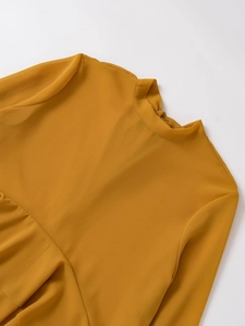 Detail of round neckline and layered chiffon fabric texture on ginger yellow blouse