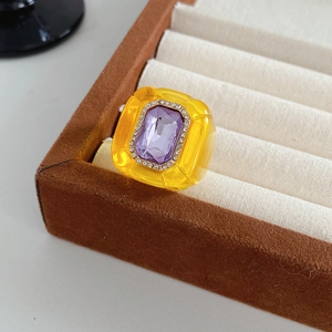 Macro d'une bague hexagonale vintage en résine avec pierre violette dans un coffret à bijoux