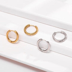 Detail of silver and gold polished geometric hoop earrings on a white minimalist display