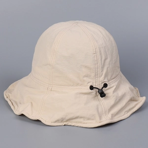Detail of beige sun bucket hat showing the adjustable black drawstring toggle and nylon texture