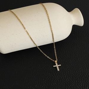 Detail of gold chain necklace with a cross pendant featuring micro-set cubic zirconia