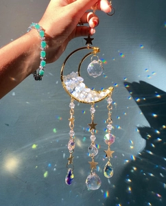 Golden moon suncatcher with amethyst stones and crystals casting rainbow spots on the wall