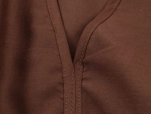 Gros plan d'une robe marron foncé montrant les coutures du col en V et la texture du tissu