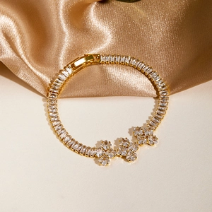 Detailed close-up of a luxury gold bracelet featuring cubic zirconia clover charms and stones
