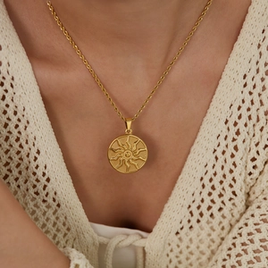 Detailed view of a gold sunburst relief pendant on a fine twisted rope chain necklace