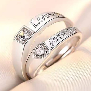 Macro detail of silver couple rings with Love and Forever engravings and round gemstones