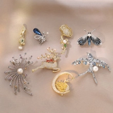 Detail view of crystal butterfly, deer, and swan brooches on beige fabric background