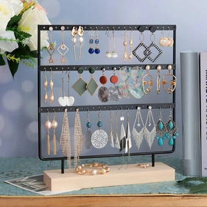 Detail view of the 3-tier black metal earring stand with a natural wooden base organizer