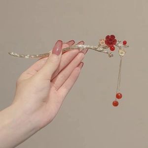 Detailed view of golden branch hair stick with red floral accents and tassel beads