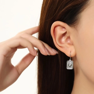 Detailed close-up of a silver rectangular starburst earring with a sparkling zircon stone