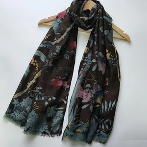 Close-up of dark brown sateen scarf with floral bird print and elegant fringe details
