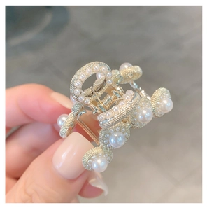 Detailed view of a gold hair claw clip decorated with elegant white pearls and small crystals