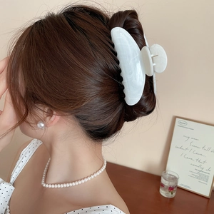 Détail de la grande pince à cheveux en acrylique marbre blanc sur modèle pour un style chic