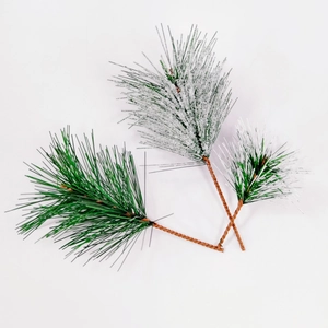 Close-up of artificial green pine needles and white snow-covered branches on white background