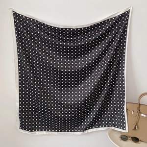 Detail view of a black silk scarf with white polka dots and letter C print pattern