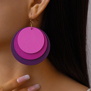 Macro detail of layered purple gradient geometric circular wooden earrings with metal hooks