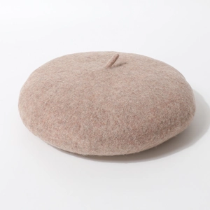 Detail van de haverkleurige wollen baret met zachte textuur en klein steeltje bovenop