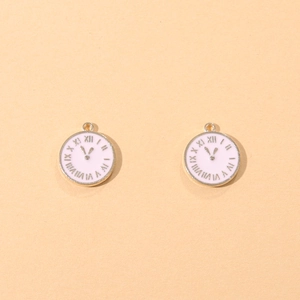 Detailed macro view of two gold-plated clock charms with white enamel and Roman numerals