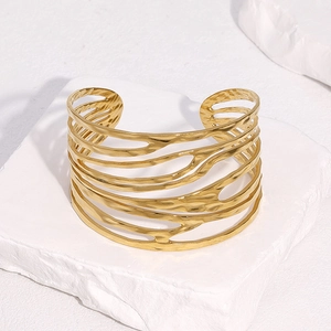 Bracciale rigido aperto largo dorato con linee irregolari traforate stile moderno