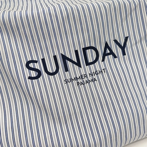 Detailed texture of blue and white striped canvas bag with Sunday letter embroidery