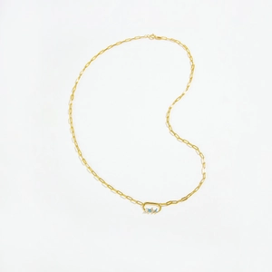 Macro view of gold paperclip chain necklace featuring a blue zircon inlaid buckle pendant