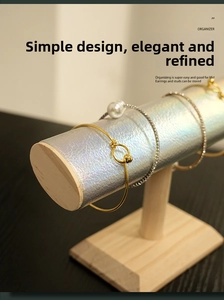 Close-up of a silver laser-texture jewelry stand with wood base displaying bracelets