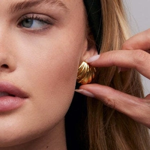 Minimalist 18K gold shell shaped earrings with wavy texture on a female model