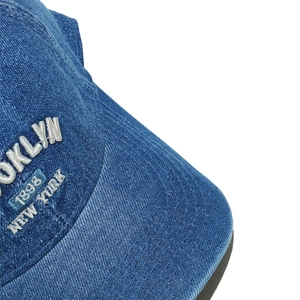 Détail de la broderie 3D blanche sur casquette en denim délavé bleu avec texte Brooklyn