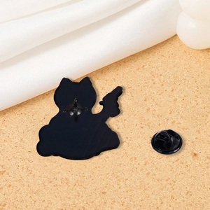 Close-up of black metal cat skeleton brooch back with butterfly clasp on fabric