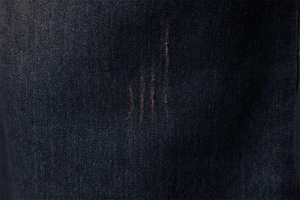 Macro view of dark blue denim fabric texture with distressed and worn details on shirt
