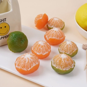 Realistic peeled orange and green tangerine prop set displayed on a white tray